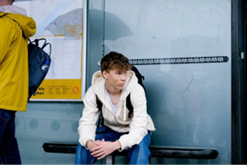 Nuori poika istuu pysäkillä.